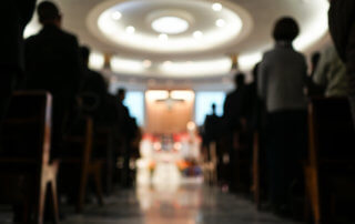 view from the aisle of a church with silhouettes of people in the pews