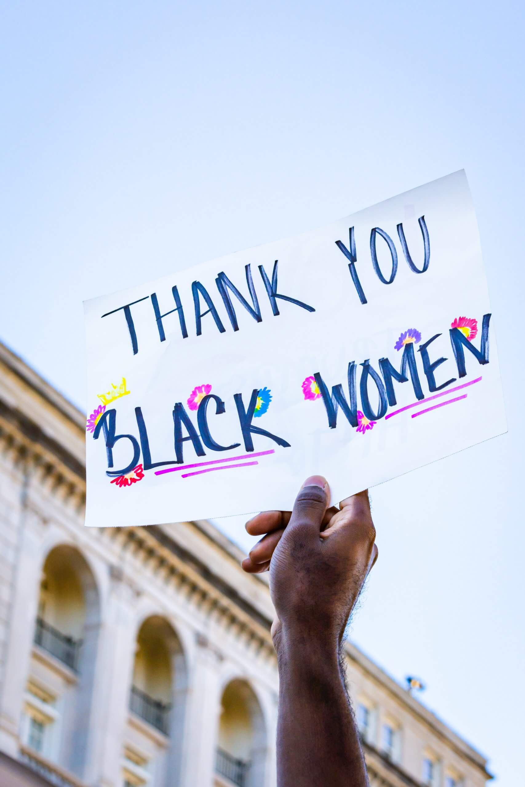 Person holding up hand written sign that says, "Thank You Black Women."