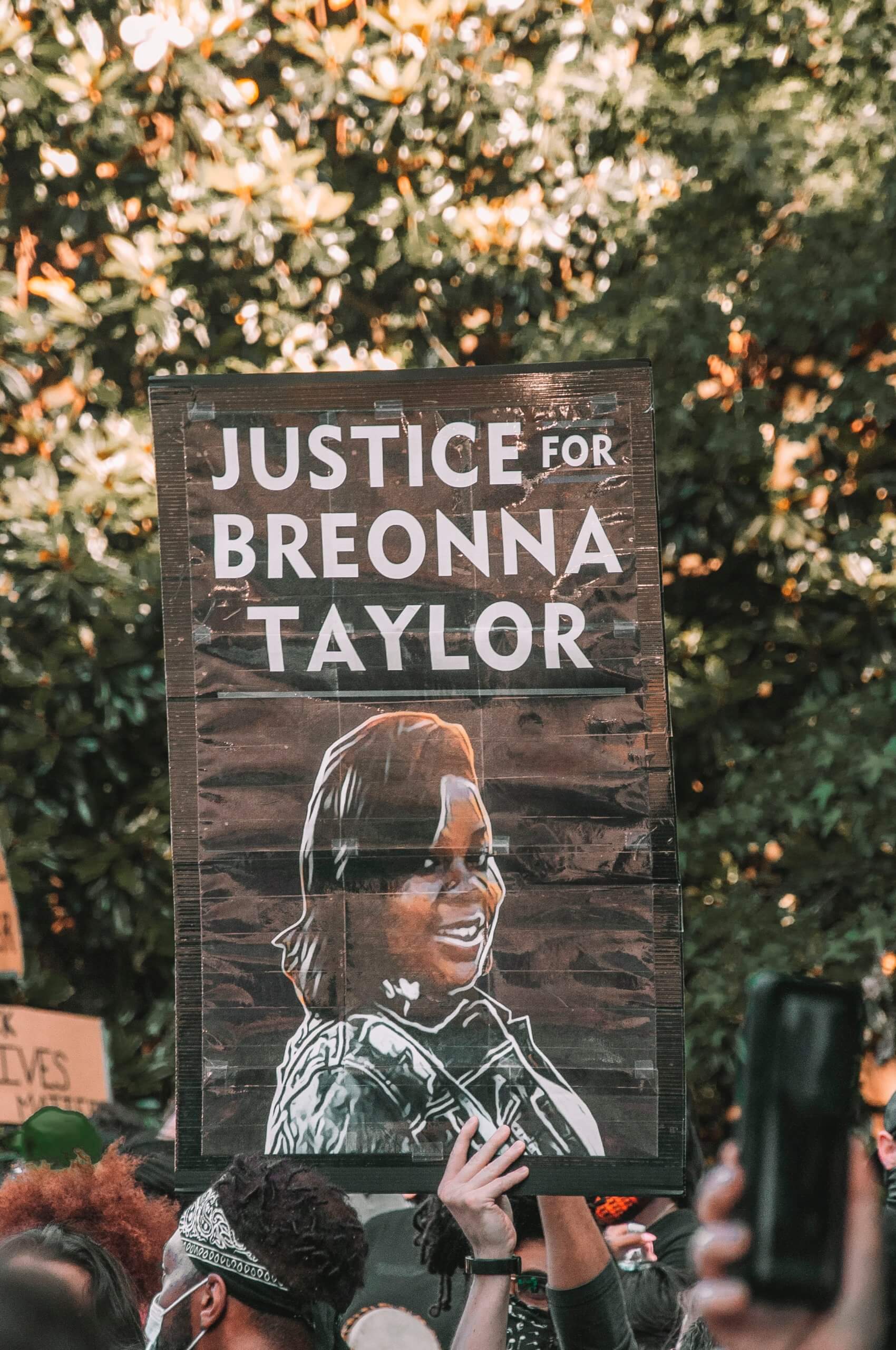 Person holding up sign that says, "Justice for Breonna Taylor" and a drawing of Breonna
