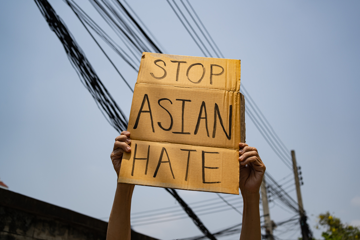 image of two hands holding Stop Asian Hate sign in the air